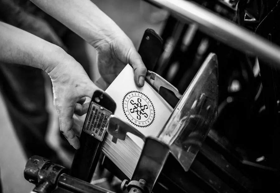 Druckbögen werden fachmännisch aus dem Ausleger der Druckmaschine genommen.